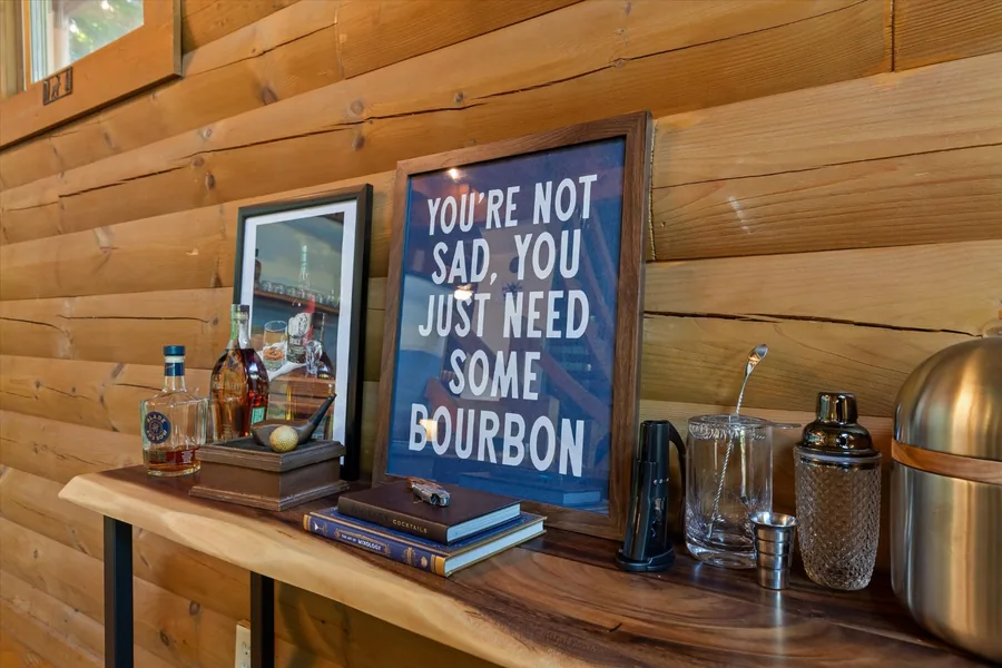 Bar console with bottles, glassware and a framed bourbon sign