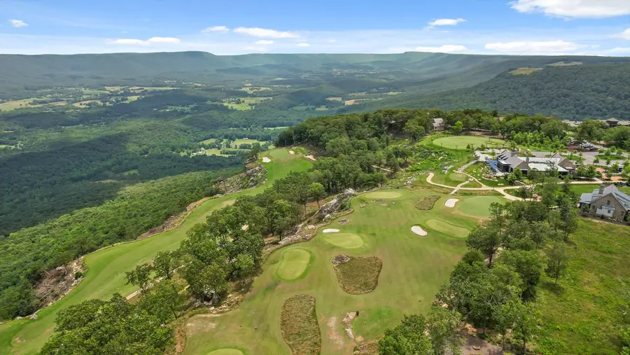 Aerial of fairways running along the mountain brow above the valley