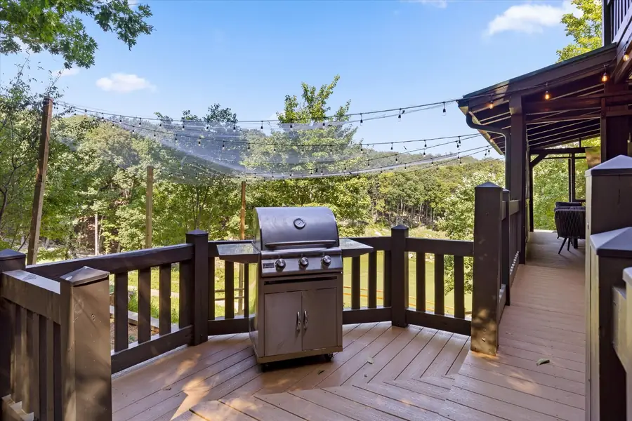 Two gas grills on a wood deck strung with lights