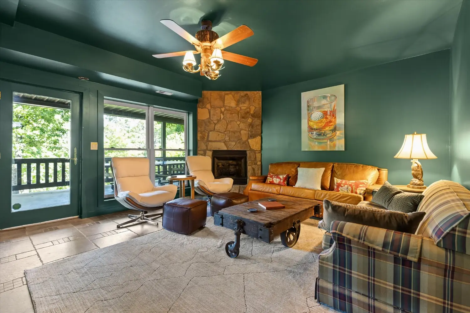 Lower level den with a stone fireplace, leather seating and armchairs