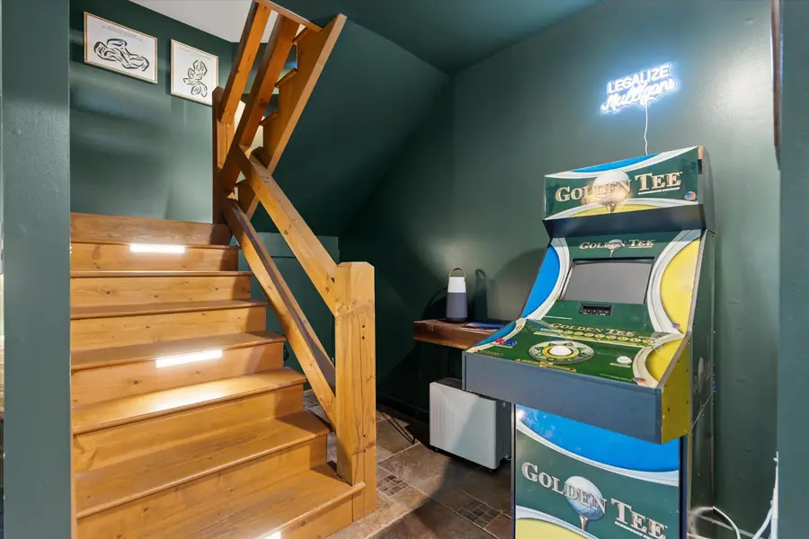 Golden Tee arcade cabinet glowing beside the stairs