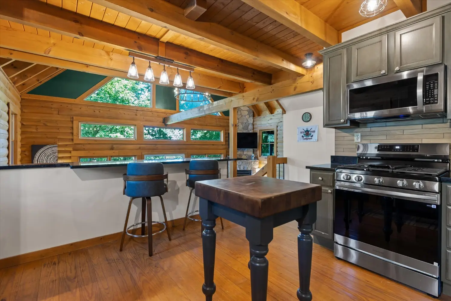 Kitchen island with bar stools beneath pendant lights and stainless appliances