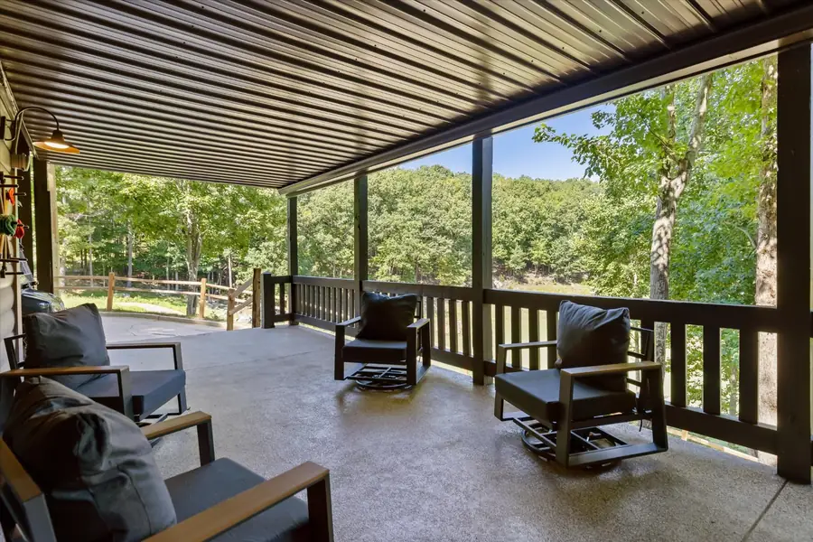 Covered lower patio with leather chairs facing the woods