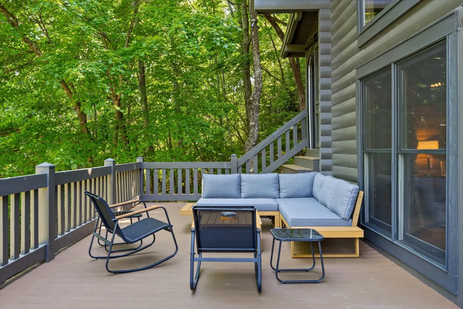 Rocking chairs and lounge seating on a covered porch above the trees