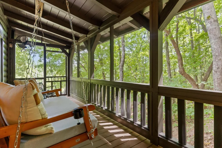 Hanging porch swing on the screened porch looking into the hardwoods