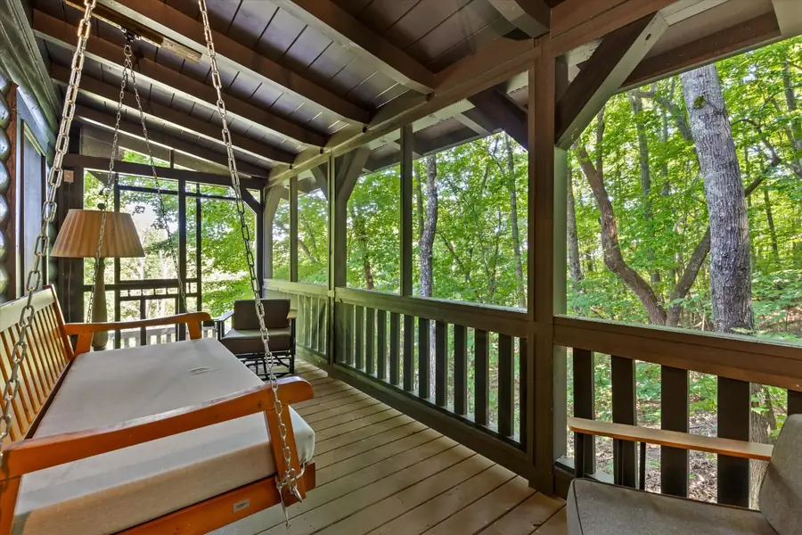 Hanging porch swing on a screened wood porch with forest views