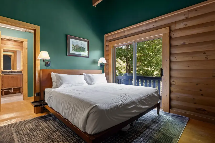King bedroom with forest green walls and adjoining bathroom
